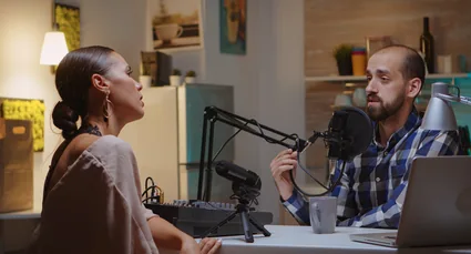 Radio presenters speaking into microphones in a studio
