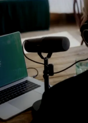 Producer preparing a podcast at a laptop and microphone