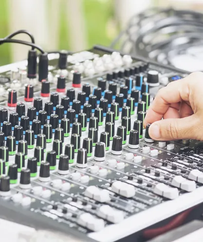 Hand adjusting a sound mixing console