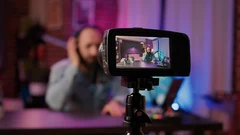 a video camera screen showing a man recording at a microphone