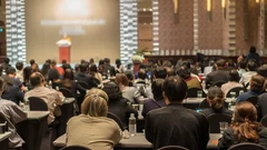 an audience in a conference hall listening to the speakers through interpreter headsets