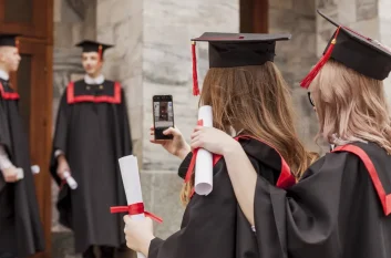 Graduates in caps and gowns recording the ceremony on a phone